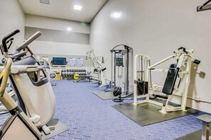 Ein Fitnessstudio mit Cardiogeräten, Gewichten und einem Fernseher.