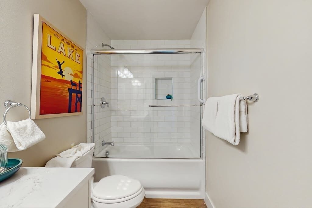 Ein Badezimmer mit einer Duschkabine, einer Toilette, einem Waschbecken mit Marmorplatte und einem Handtuchhalter.