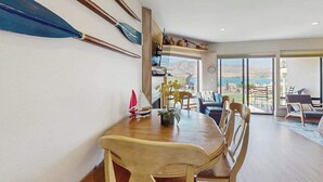 Un comedor con mesa y sillas de madera, un modelo de velero y vistas panorámicas a través de amplios ventanales.