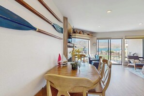 Ein Essbereich mit Holztisch und Stühlen, einem Modell eines Segelbootes und Blick durch große Fenster.