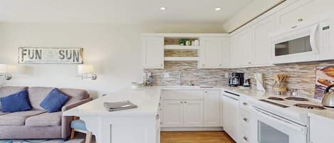 A modern kitchen with white cabinetry, a microwave, and a coffee maker.
