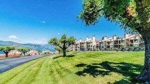 Un hotel con una fila de habitaciones, un césped cuidado y vistas a la montaña.