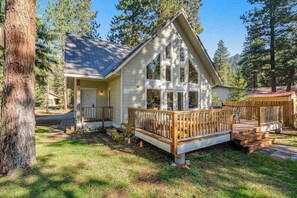 Eine Holzhütte mit einer Holzterrasse, einer Veranda und einer Garage.