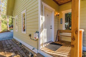 Une maison avec une porte d’entrée, un petit porche et un banc en bois.