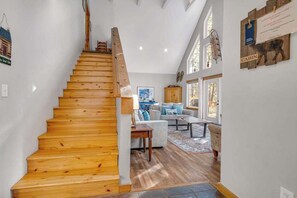 Eine Holztreppe führt zu einem Wohnbereich mit Sofa und Couchtisch.