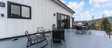A rooftop patio with outdoor furniture and a glass door leading to an interior space.