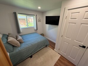 Une chambre à coucher avec un lit, une fenêtre, un téléviseur et une porte.