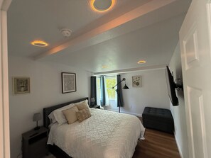 A bedroom with a bed, bedside table, lamp, and a window with curtains. - Whisper Valley Villa. New Remodel. Hot Tub! Fenced back yard, High speed WiFi. (Eureka)