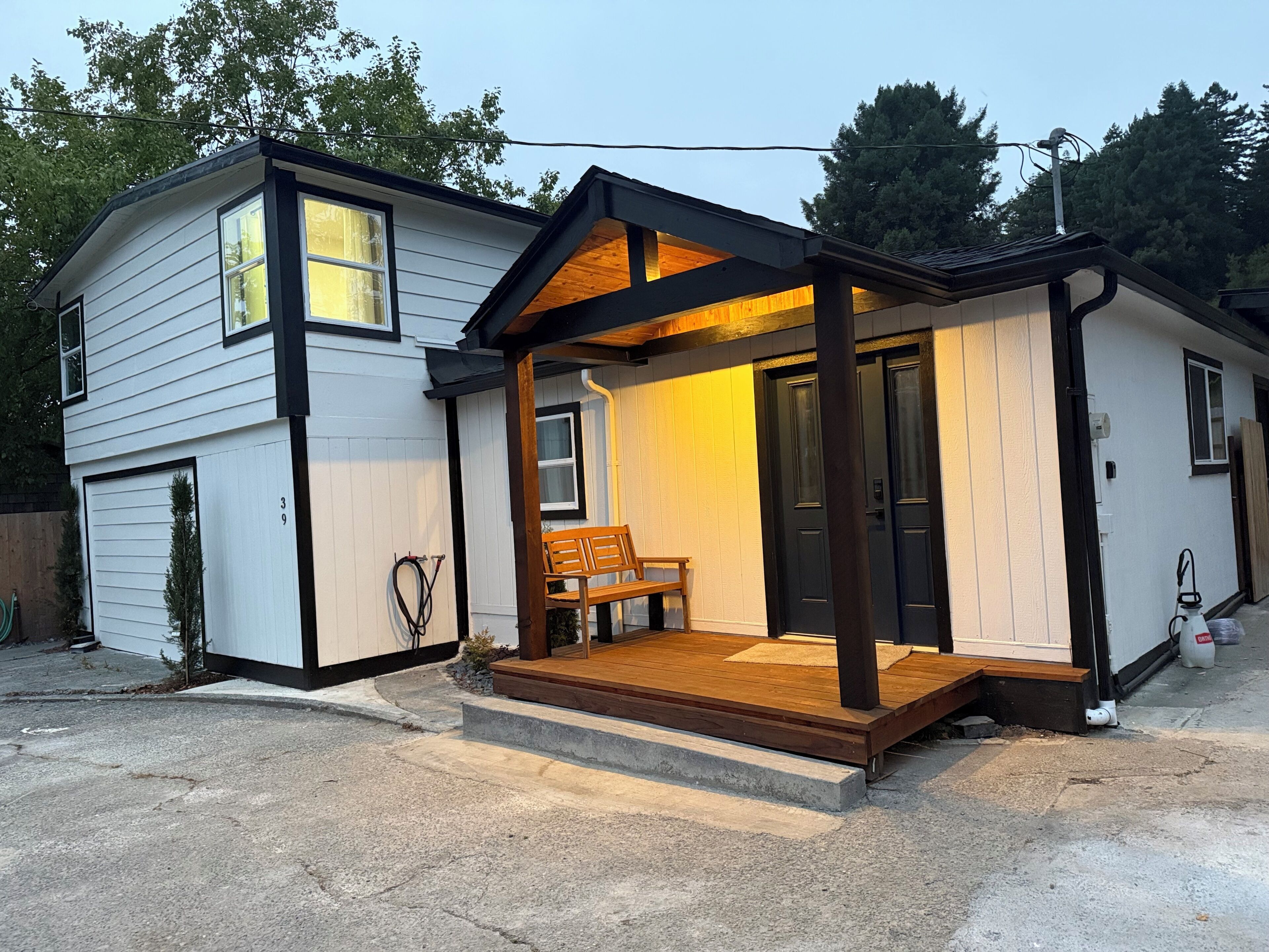 Ein zweistöckiges Haus mit Veranda, Bank und Garage.