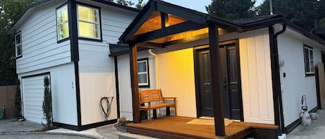 Ein zweistöckiges Haus mit Veranda, Bank und Garage.
