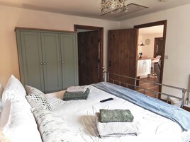 Un dormitorio con cama, almohadas, una colcha, un control remoto y un armario.