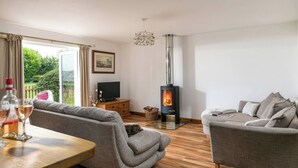 A living room with a fireplace, two sofas, a TV, and a table with glasses and a bottle.