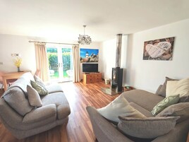Una sala de estar con sofá, televisor, chimenea y comedor con mesa y sillas.