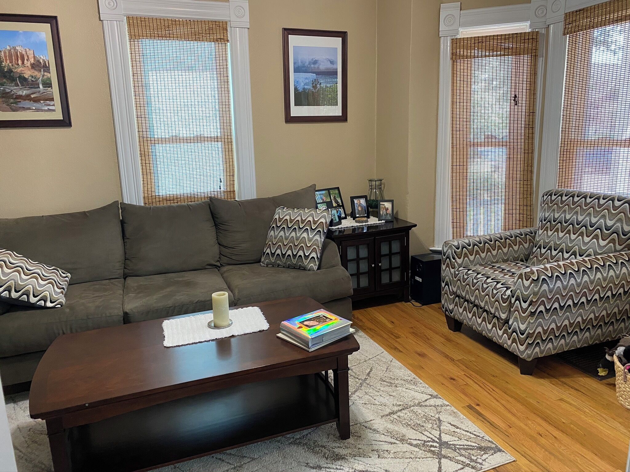 A living room with a sofa, armchair, coffee table, and a small cabinet.