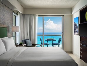 A hotel room with a large bed, a balcony with a view of the sea, a small table, and a chair. - Cancun One Bedroom Villa Westin Lagunamar Resort (Cancún)