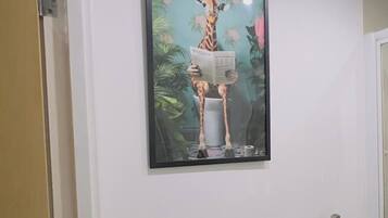 A framed picture of a giraffe reading on a wall in a hallway.