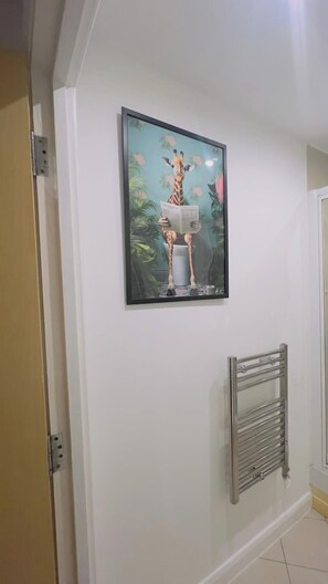 Cuadro enmarcado de una jirafa leyendo en una pared del pasillo.