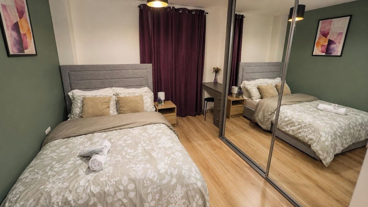 Una habitación de hotel con dos camas, un escritorio y un espejo.