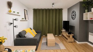 Una sala moderna con un sofá gris, una mesa de centro de madera y un televisor de pantalla plana.