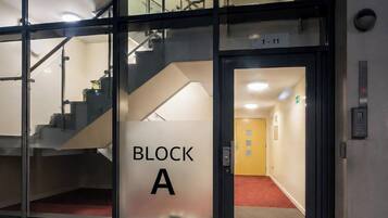 Ein Hotel Eingang mit einer Glastür, auf der 'BLOCK A' steht, und einer Innentreppe.
