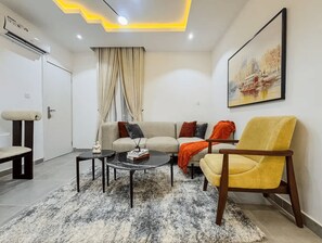 Uma sala de estar moderna com um sofá, poltrona, mesa de centro e um quadro na parede.