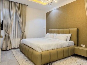 Ein modernes Schlafzimmer mit einem großen Bett, einem Nachttisch und einem an der Wand montierten Fernseher.