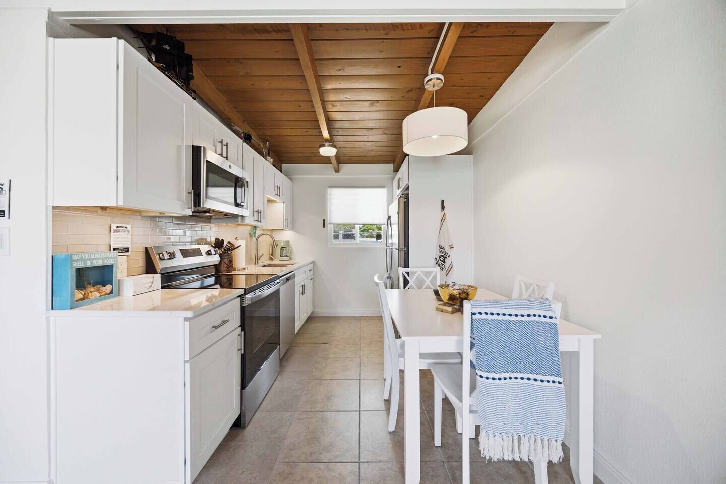 A compact kitchen with white cabinets, a microwave, and a dining area with a table and chairs.