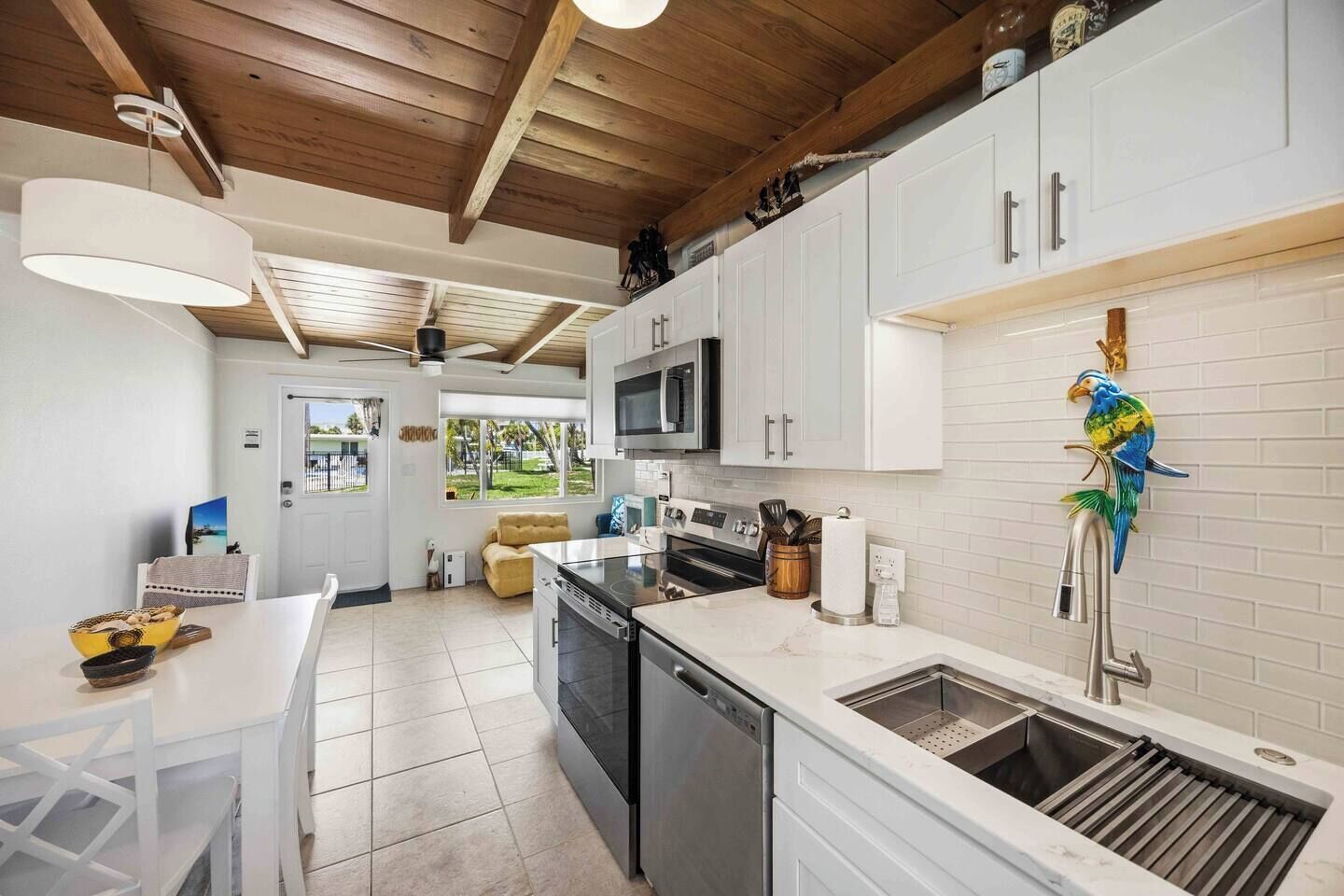 A modern kitchen with white cabinetry, a built-in microwave, and a stainless steel sink.