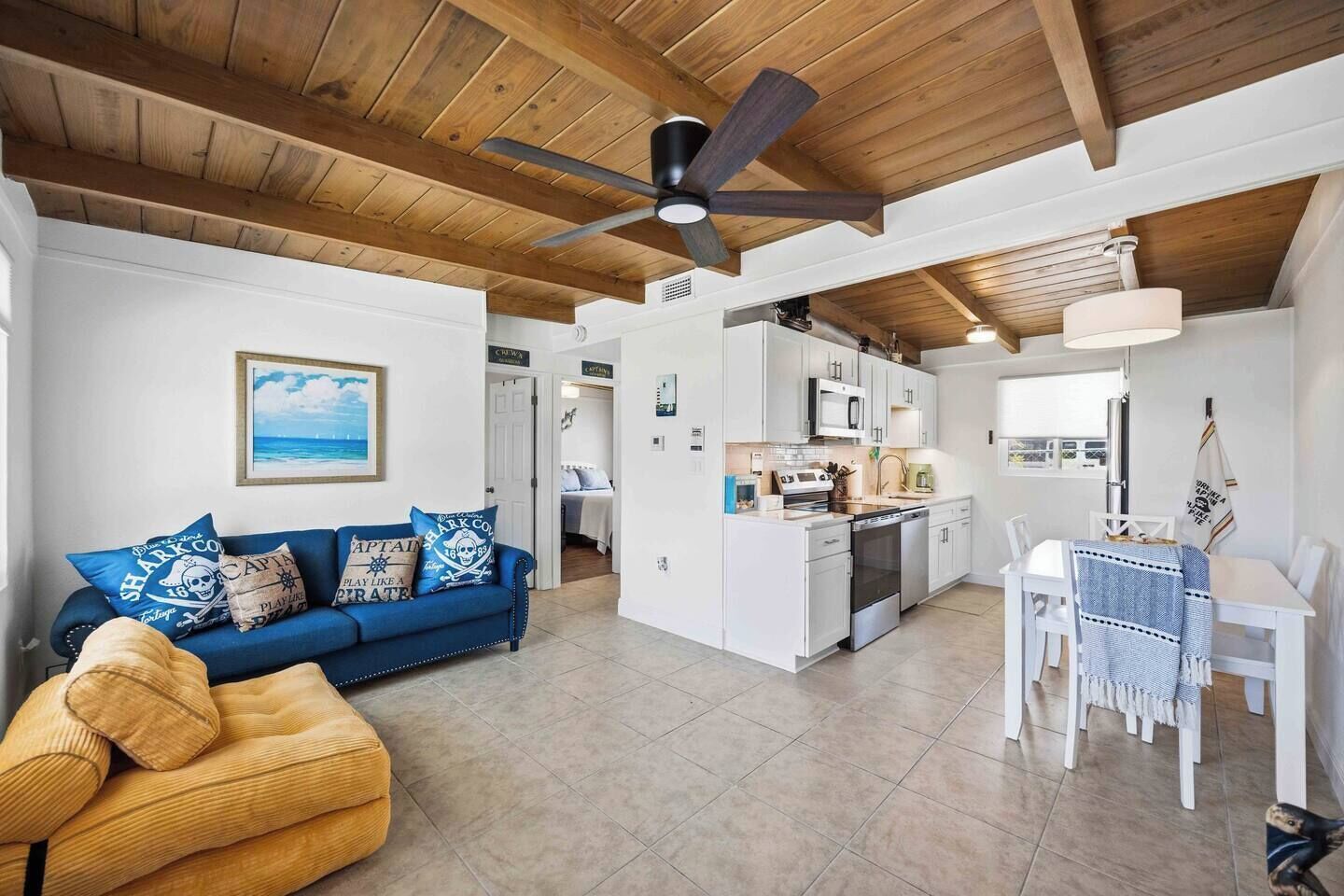 A modern living space with a blue sofa, a dining area, and a kitchen.