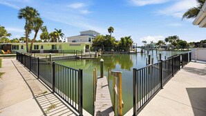 A waterfront property with a dock, a pool, and a building with a green facade. - Pirate's Paradise | Manasota Key Beach Condo | Dock & Pool (Englewood)