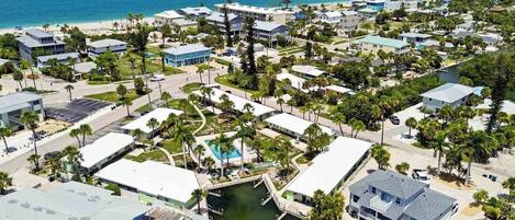 An aerial view of a coastal residential area with multiple buildings, a marina, and a beach.
