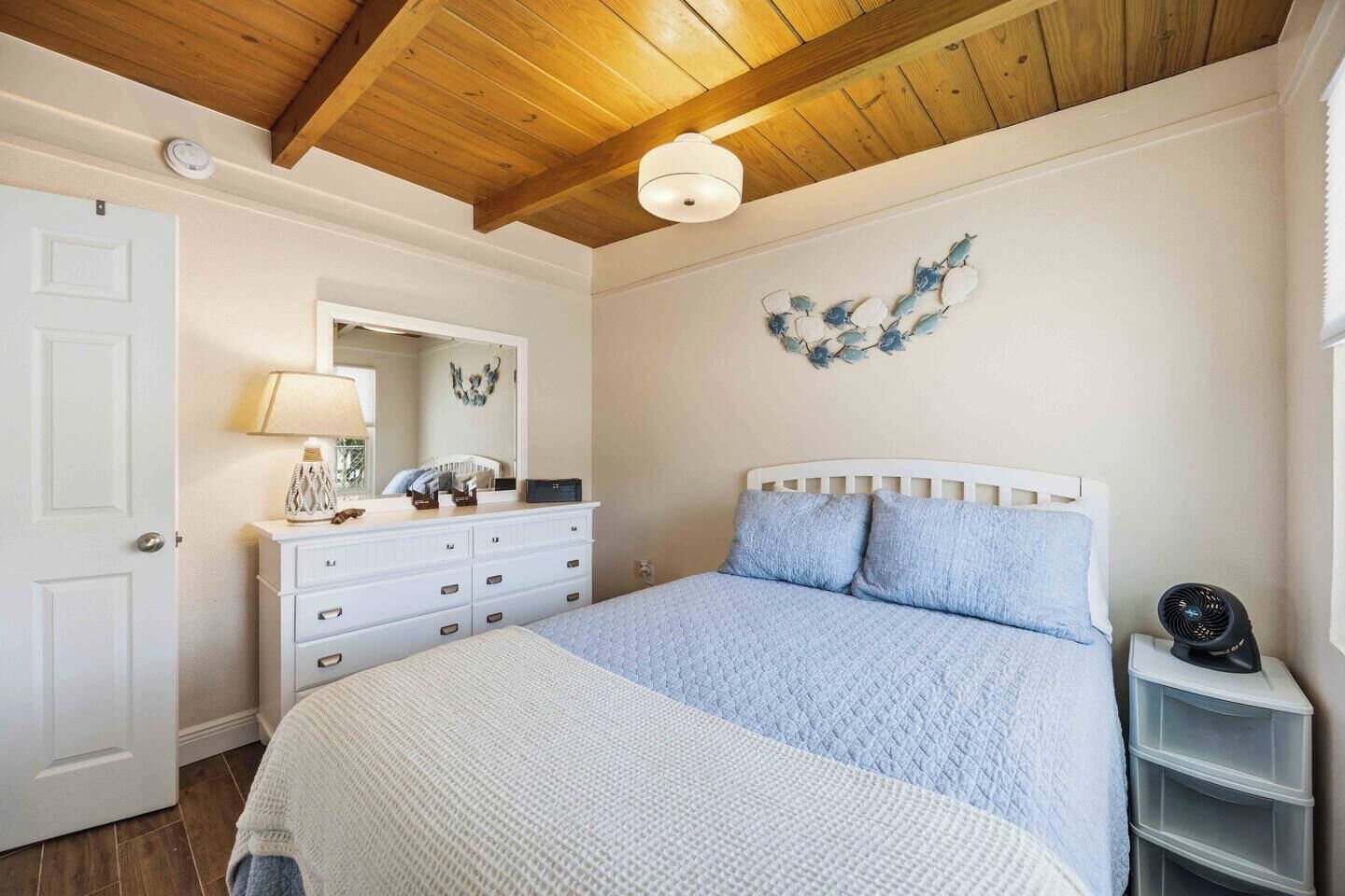 Une chambre à coucher comprenant un lit, une commode, un miroir et des éléments de décoration murale.