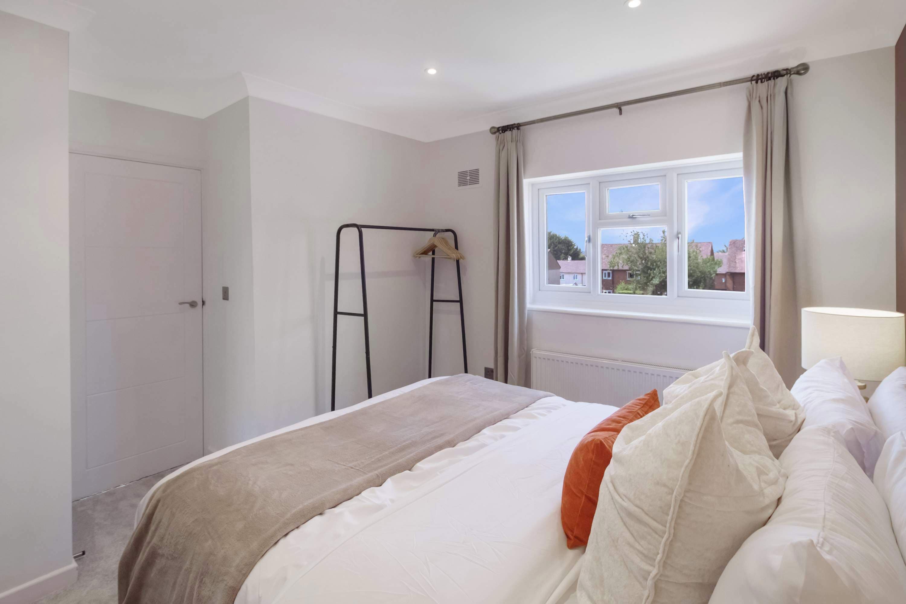A bedroom with a bed, a window, a radiator, and a wardrobe.