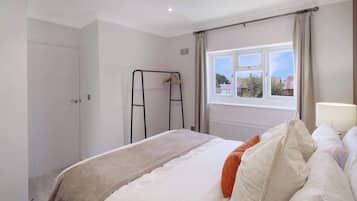 Un dormitorio con cama, ventana, radiador y armario.
