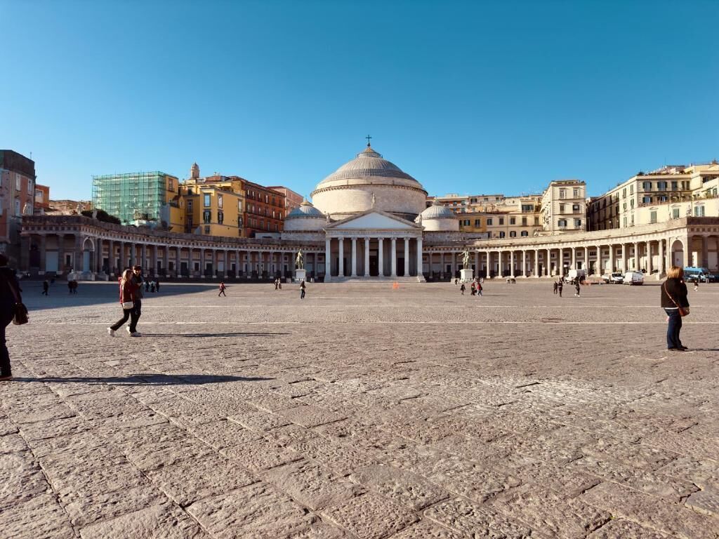 A spacious public square with a prominent building featuring a dome and columns in the center.
