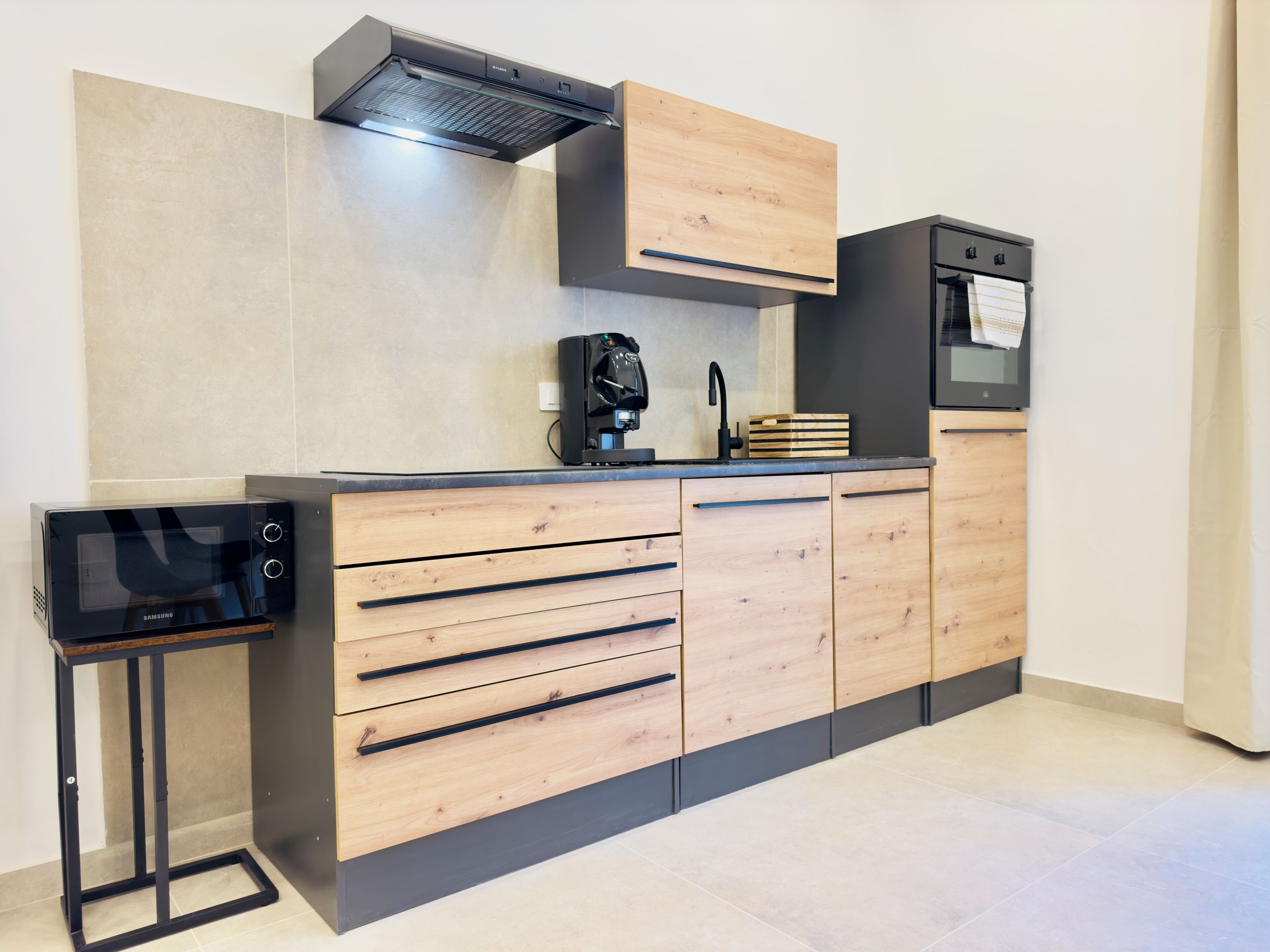 Una cucina moderna con forno a incasso, microonde e una macchina per il caffè.