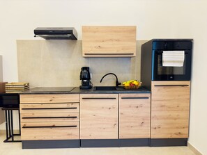 Una cocina moderna con armarios de madera, cafetera, lavabo y refrigerador.