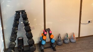 Ein Heimfitnessraum mit verschiedenen Kurzhanteln, einer Kettlebell und einer Yogamatte.