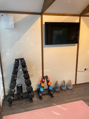 Un gimnasio en casa con varios mancuernas, una pesa rusa y una colchoneta para yoga.