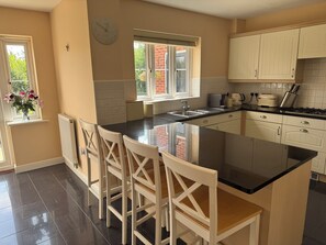 Una cocina con una isla central, muebles blancos y un reloj en la pared.
