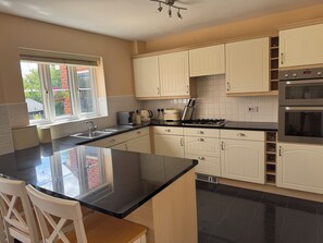 A kitchen with a central island, white cabinets, a black countertop, and stainless steel appliances.