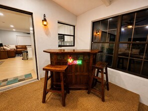 A bar area with stools, a neon sign, and a window with blinds. - The Tiki Hideaway - Indoor Pool. Tiki Bar. Modern Beach Vibes (Homosassa)