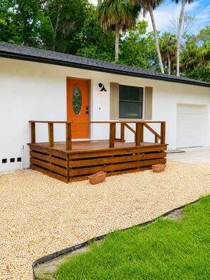 A house with a wooden deck, a white exterior, and a garage. - The Tiki Hideaway - Indoor Pool. Tiki Bar. Modern Beach Vibes (Homosassa)