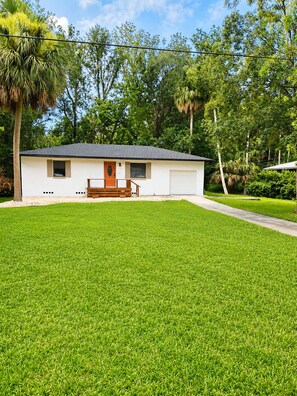 A single-story house with a front porch, a garage, and a well-maintained lawn. - The Tiki Hideaway - Indoor Pool. Tiki Bar. Modern Beach Vibes (Homosassa)