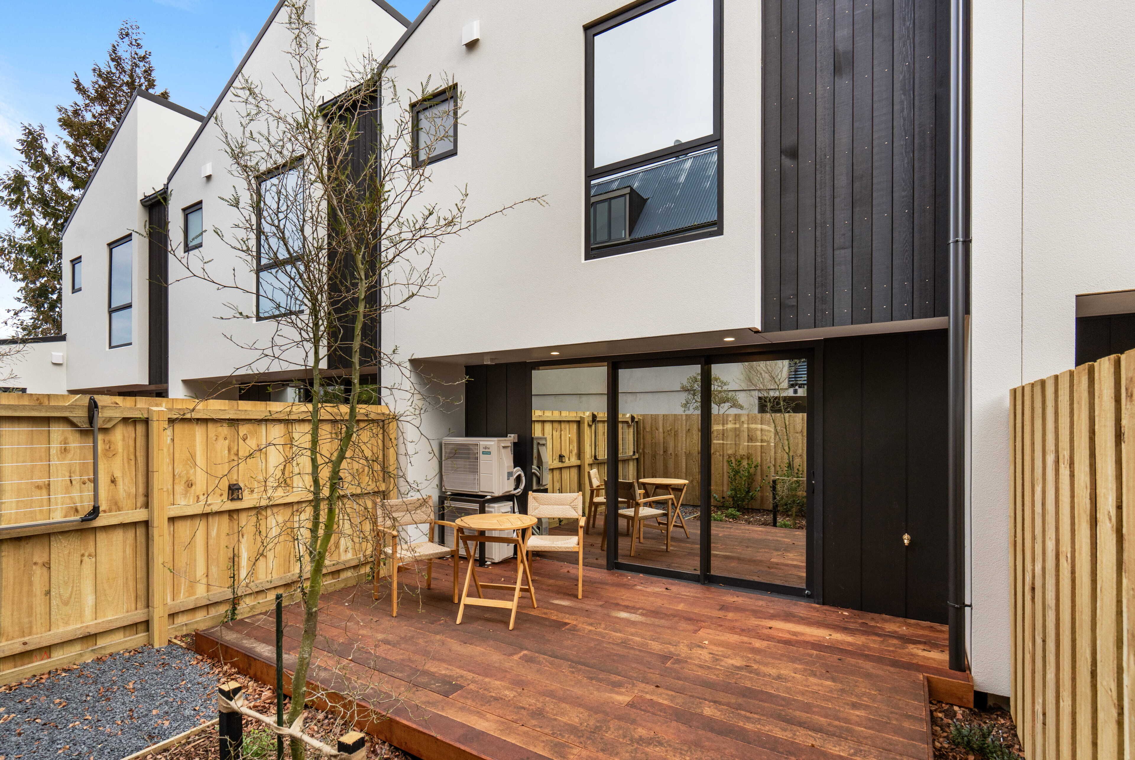 Ein modernes Wohngebäude mit Terrasse, Gartenmöbeln und einer Holzterrasse.