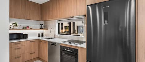 Een moderne keuken met houten kastjes, een roestvrijstalen koelkast, een inbouwoven en een magnetron.