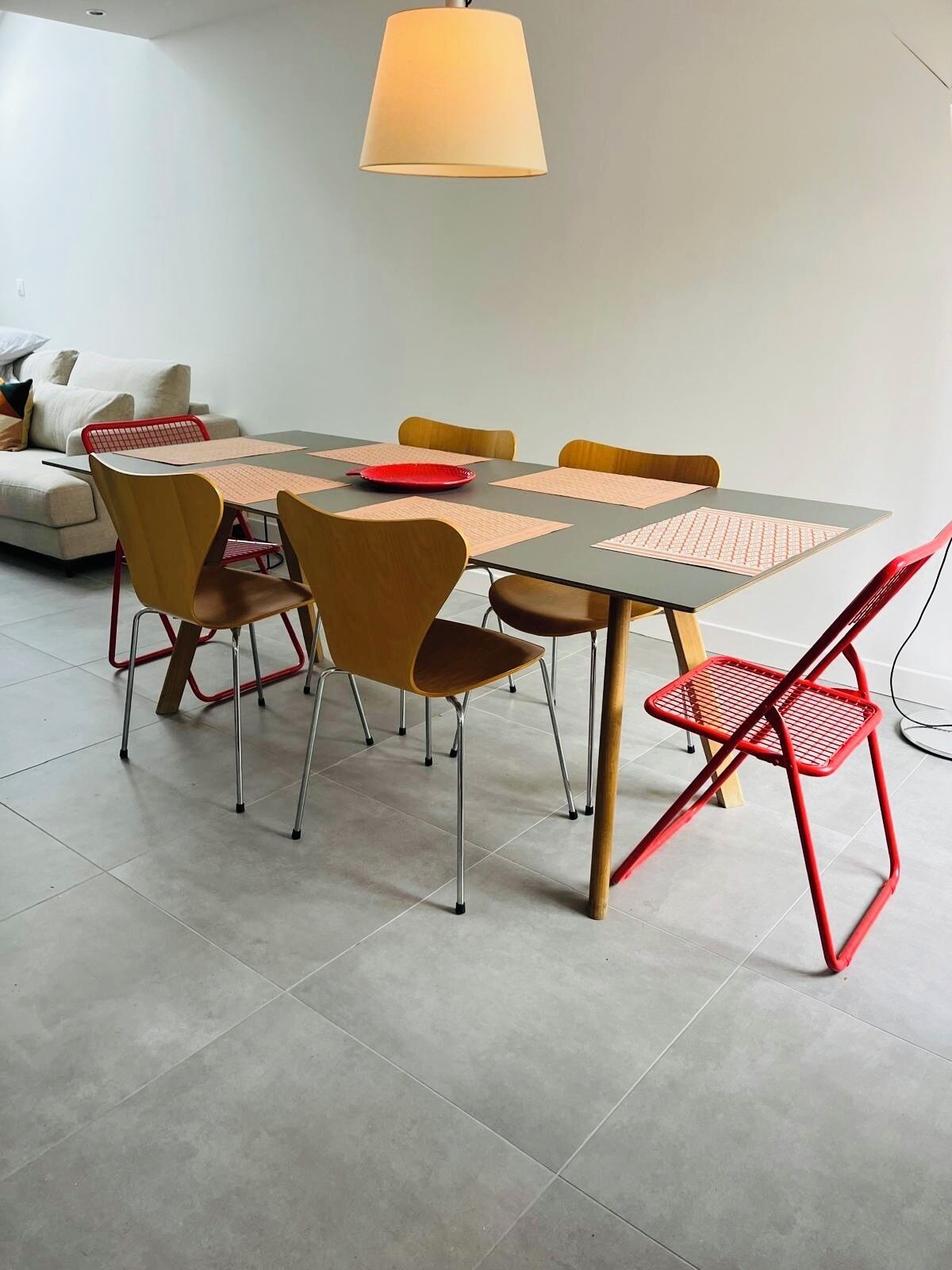 A modern dining area with a table, chairs, and a hanging light fixture.