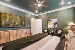 Ein Schlafzimmer mit Bett, Kleiderschrank, Deckenventilator, einem Gemälde und einem Nachttisch mit Lampe.