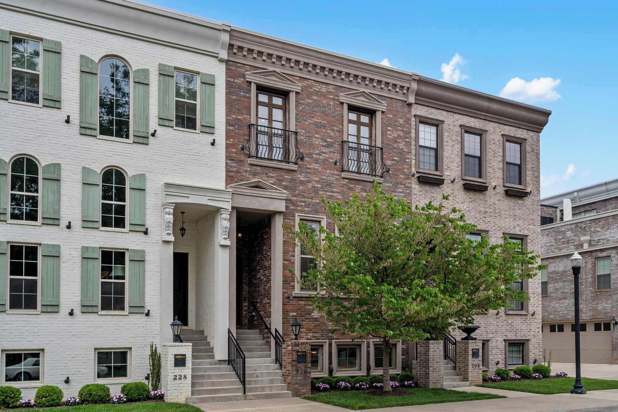 A two-story building with a brick facade and white walls, featuring a central entrance with steps and a small porch.