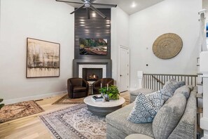 Een zithoek met een open haard, twee fauteuils, een salontafel met decoratieve objecten, een groot abstract schilderij en een ronde wandversiering.